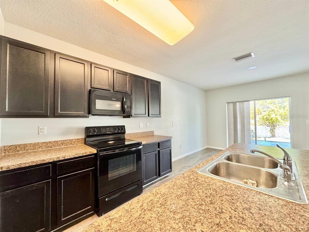 35743 Hillbrook Avenue Zephyrhills, FL 33541 - Photo 15 of 44 a kitchen with granite countertop a sink stove and refrigerator