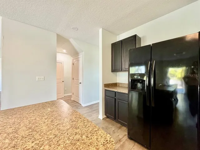 a kitchen with stainless steel appliances kitchen island granite countertop a refrigerator and a sink