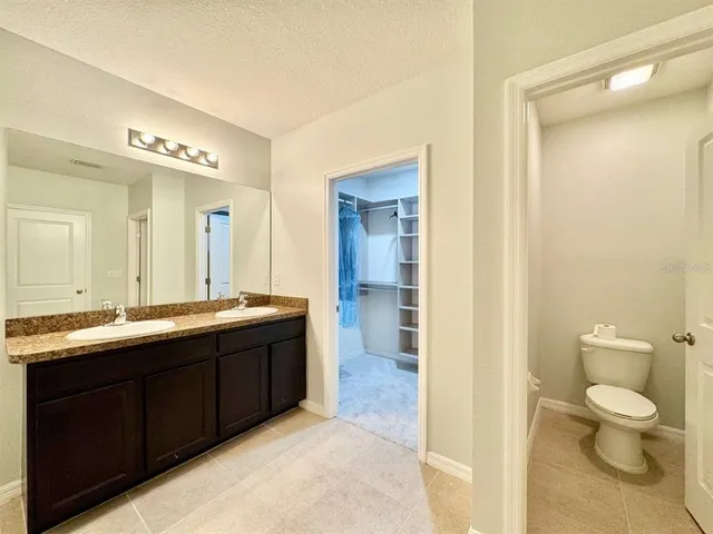 a spacious bathroom with a double vanity sink toilet mirror and a shower