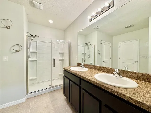 a bathroom with a granite countertop sink a shower a mirror and a bathtub