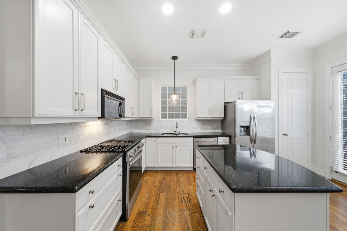 1736 Colquitt Street, Unit A Houston, TX 77098 - Photo 13 of 45 Freshly painted dove-grey cabinets and updated fixtures add a refined, cohesive feel to the kitchen’s bright, marble-accented design.