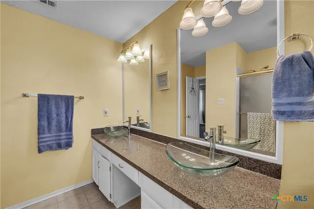 a bathroom with a granite countertop double vanity sink and a mirror