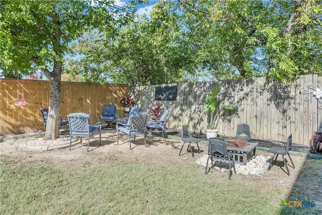 a view of backyard with a table and chairs and a large tree