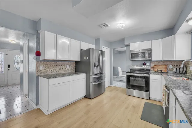 a kitchen with granite countertop a refrigerator stove top oven and sink