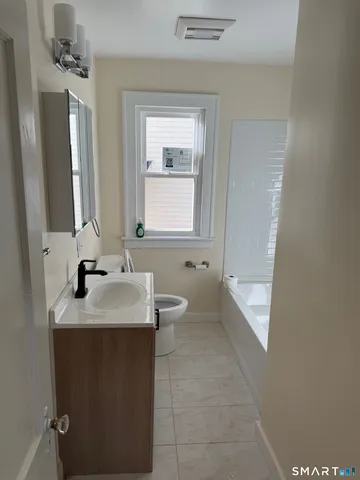 a bathroom with a granite countertop sink toilet and mirror
