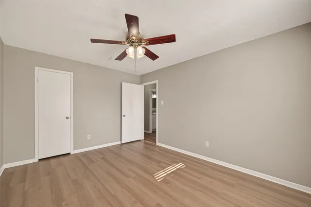 an empty room with wooden floor fan and windows