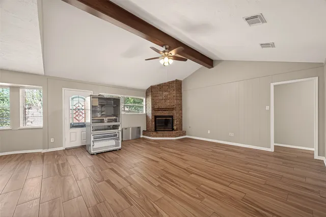 an empty room with wooden floor fireplace and windows