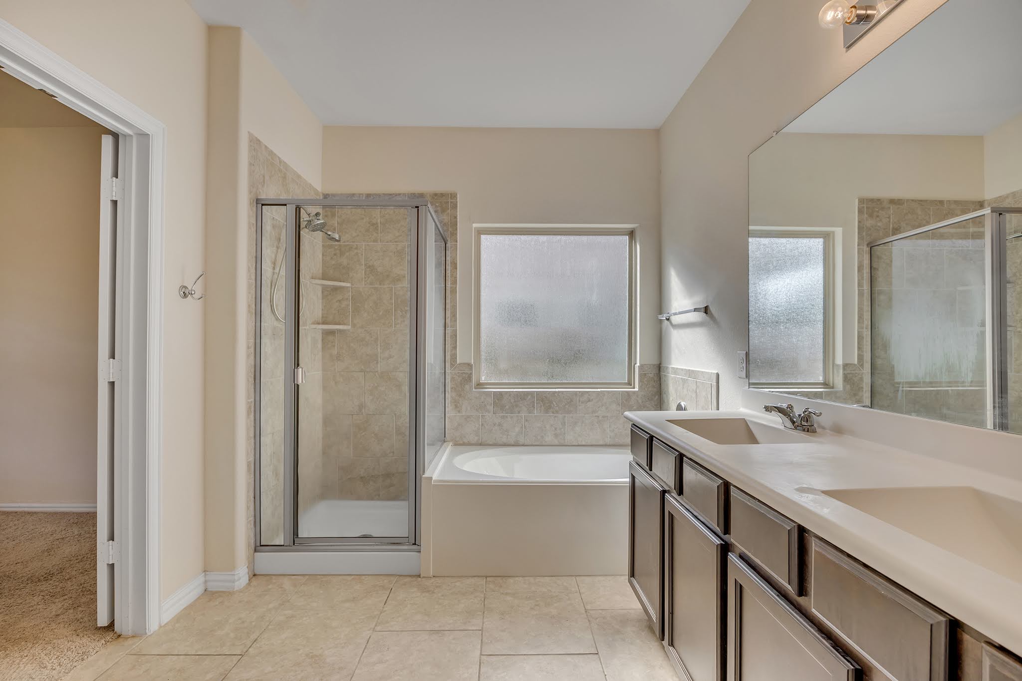 7212 Vail Ridge Street Austin, TX 78744 - Photo 18 of 26 Dual vanities complement a bright bathroom featuring a soaking tub and walk-in shower.
