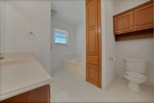 a bathroom with a granite countertop sink a toilet and bathtub
