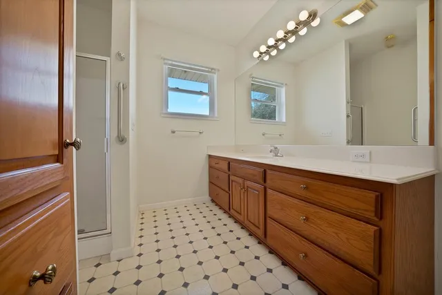 a spacious bathroom with a double vanity sink a large mirror and a shower