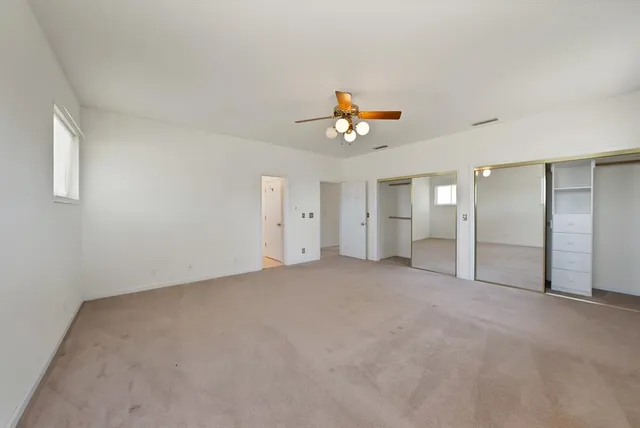 an empty room with a kitchen and a chandelier fan