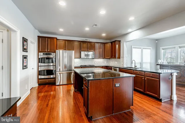 a large kitchen with stainless steel appliances granite countertop a stove and a refrigerator