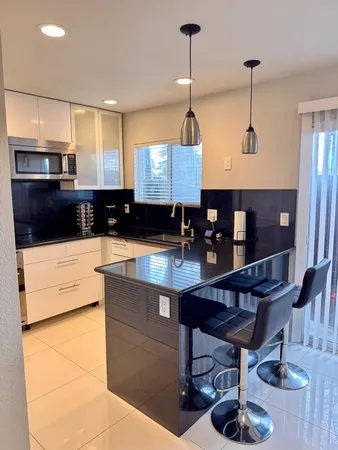 a kitchen with stainless steel appliances kitchen island granite countertop a sink a stove a refrigerator and cabinets