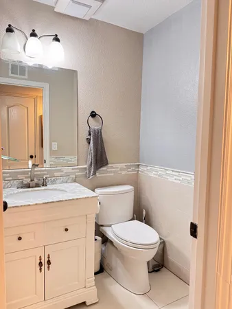 a bathroom with a granite countertop toilet sink and mirror