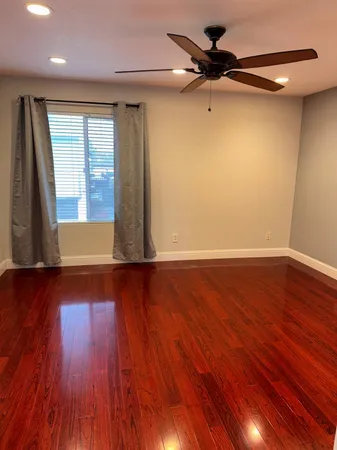 a view of an empty room with wooden floor and a window
