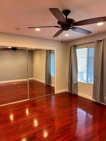 a view of an empty room with window and wooden floor
