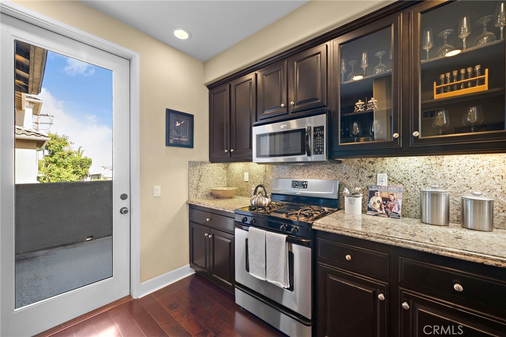 8028 Monaco Stanton, CA 90680 - Photo 3 of 35 granite countertops, full granite backsplash, rich dark-wood soft-closing cabinetry with glass display panels and under-cabinet lighting