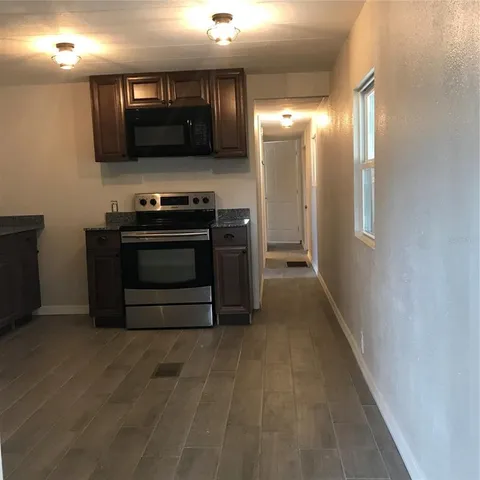 a view of kitchen with stainless steel appliances wooden floor sink and stove