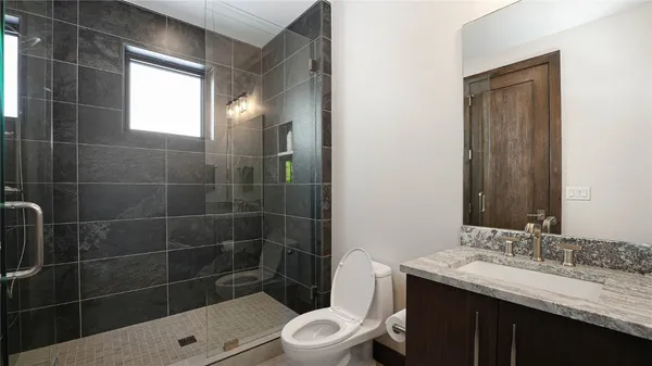 a bathroom with a sink a toilet a mirror and shower