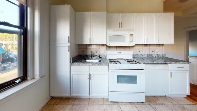 a kitchen with granite countertop white cabinets and white appliances