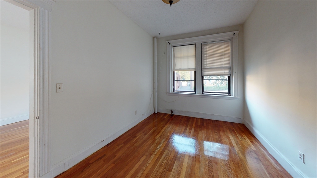 185 Chestnut Hill Avenue, Unit 5 Boston, MA 02135 - Photo 2 of 7 an empty room with wooden floor and windows