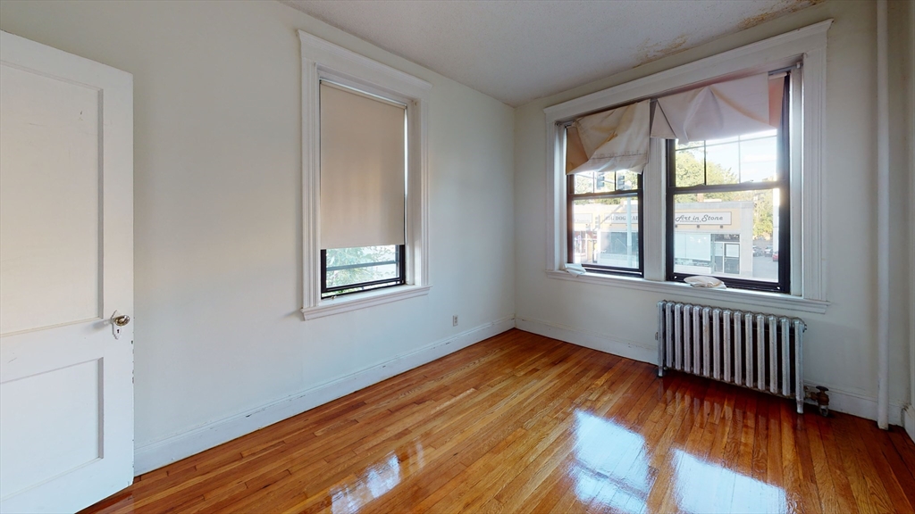 185 Chestnut Hill Avenue, Unit 5 Boston, MA 02135 - Photo 3 of 7 an empty room with wooden floor and windows