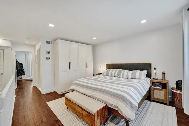 a spacious bedroom with a bed and a wooden floor