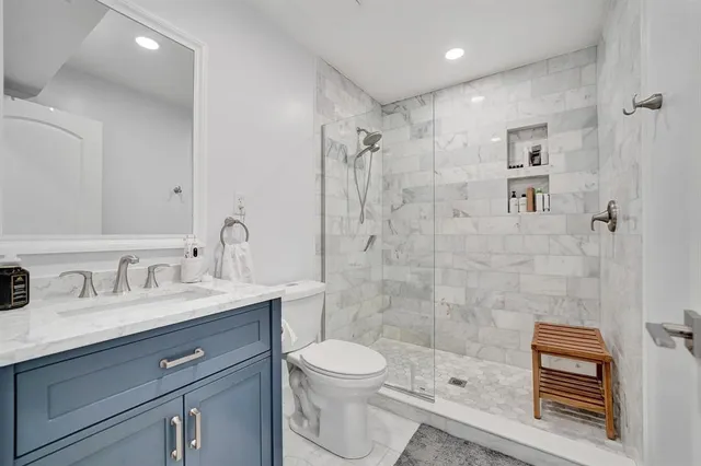 a bathroom with a granite countertop sink a toilet and shower