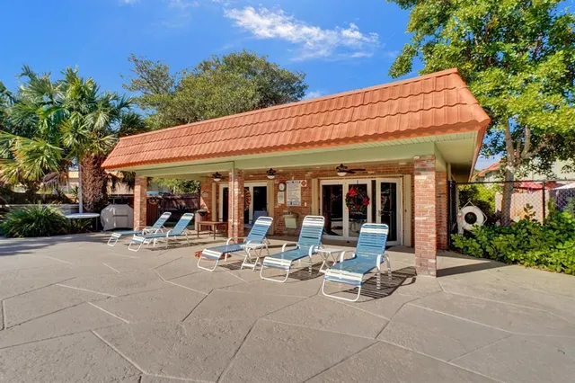 a view of a patio with dining table and chairs under an umbrella with large trees