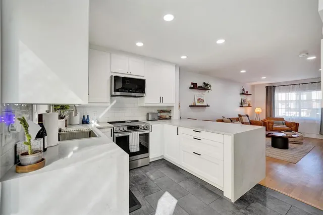 a kitchen that has a lot of white cabinets and stainless steel appliances