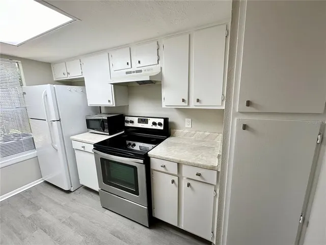 a kitchen with white cabinets and white stainless steel appliances and refrigerator