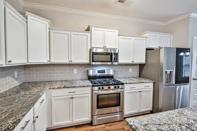 a kitchen with white cabinets and stainless steel appliances