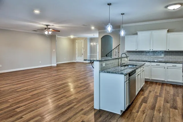 a kitchen with kitchen island granite countertop wooden floors stainless steel appliances a sink and cabinets