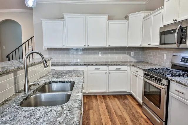 a kitchen with granite countertop a sink stainless steel appliances and cabinets