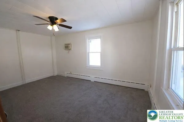 an empty room with windows and fan