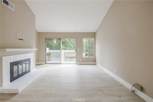 a view of an empty room with a fireplace and a window