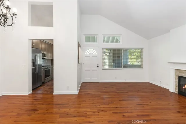 a view of an empty room with window and wooden floor