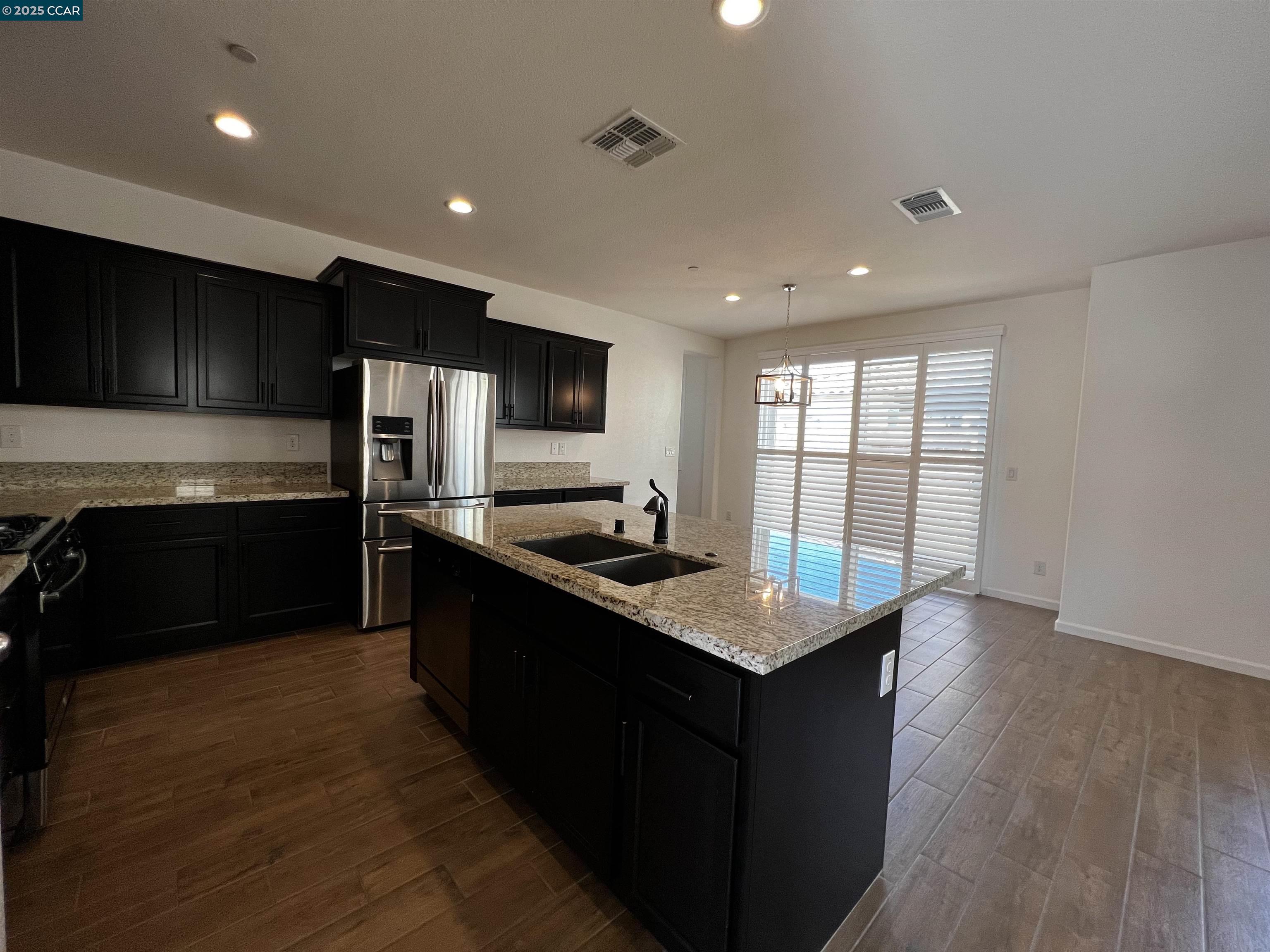742 Iris Drive Vacaville, CA 95687 - Photo 4 of 23 a kitchen with granite countertop a stove top oven a sink dishwasher a refrigerator and white cabinets with wooden floor