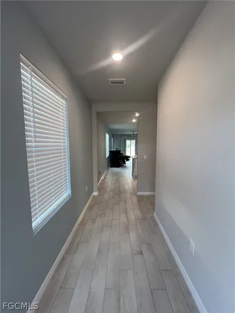 an empty room with a chandelier fan and windows