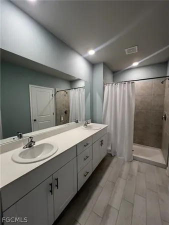 a large white bathroom with a double vanity sink a large mirror and shower