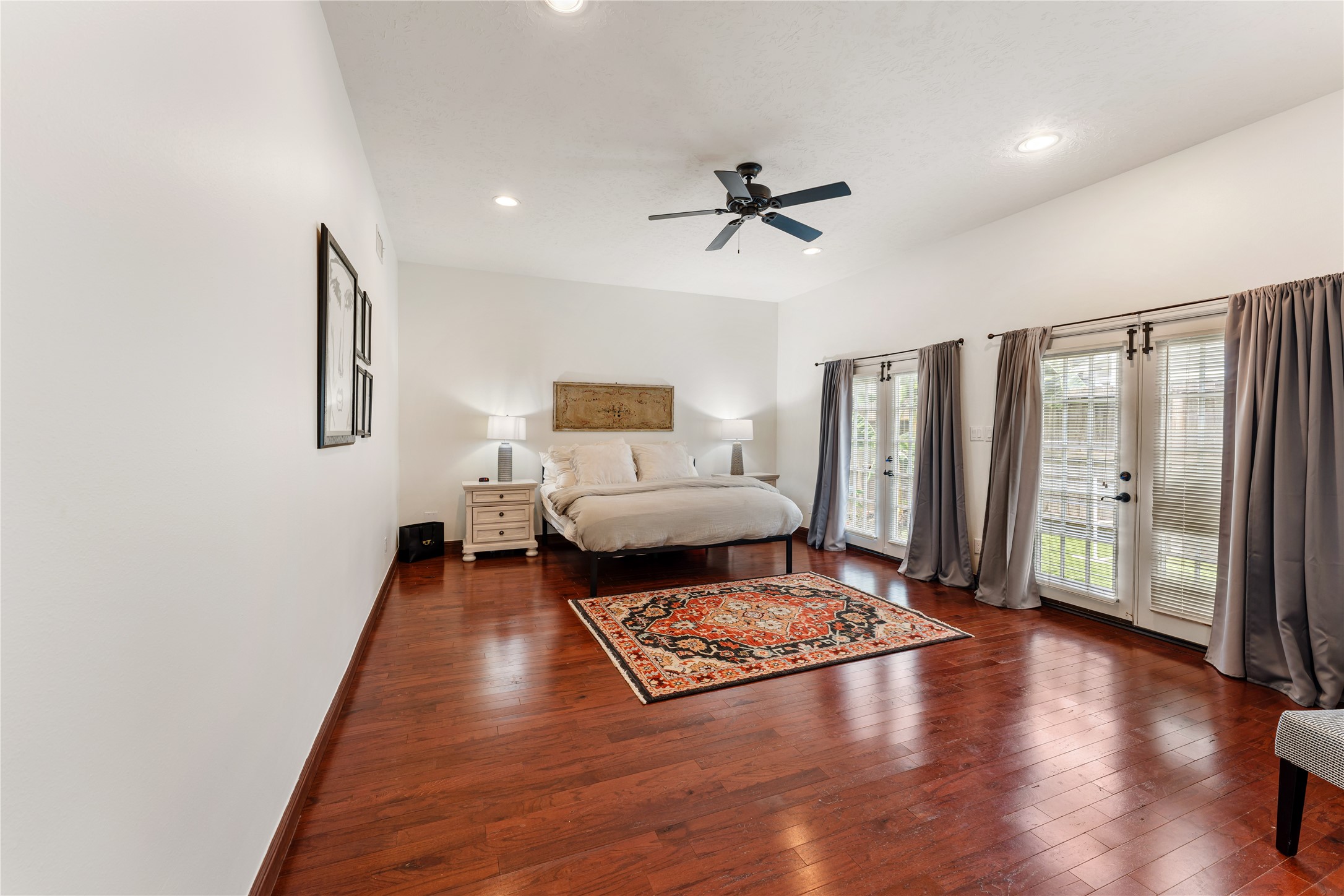 415 West 8th Street Houston, TX 77007 - Photo 16 of 39 The expansive primary suite offers a peaceful sanctuary with generous proportions, abundant natural light, and warm hardwood floors. French doors provide a beautiful connection to the private backyard, creating a tranquil indoor-outdoor atmosphere. Designed for both relaxation and everyday luxury, this retreat feels spacious, bright, and inviting.