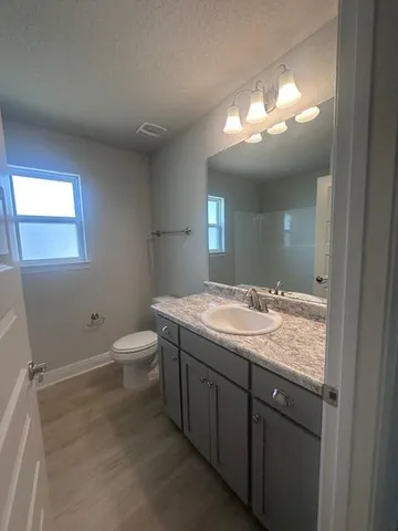 a bathroom with a granite countertop sink a toilet and a mirror