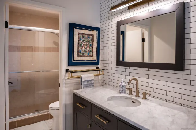 a bathroom with a granite countertop sink toilet and shower