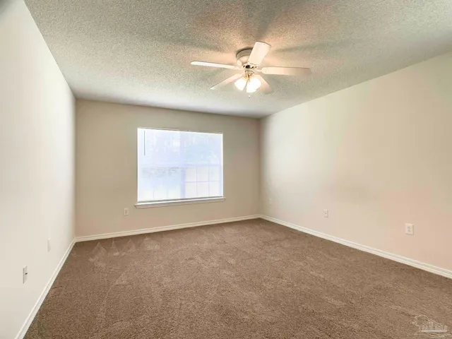 an empty room with a window and a fan