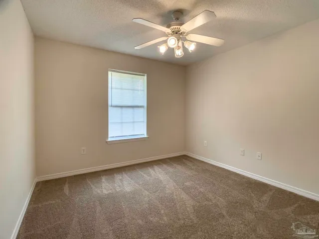 an empty room with a chandelier fan and windows
