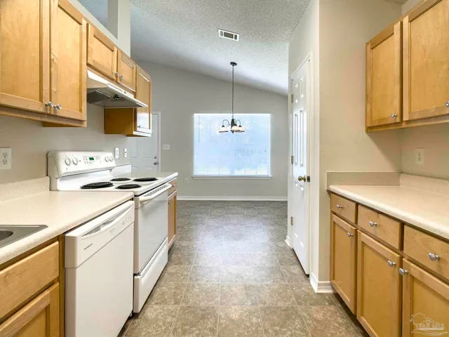 a kitchen with granite countertop a sink stove and cabinets