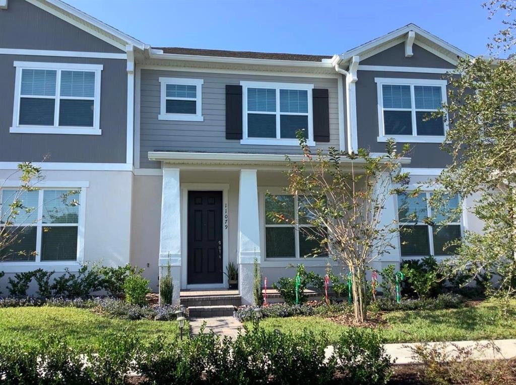 front view of a brick house with a yard and plants