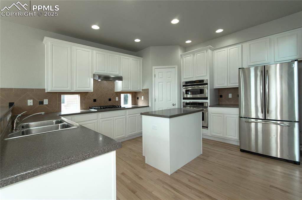 9443 St.George Road Peyton, CO 80831 - Photo 15 of 45 a kitchen with stainless steel appliances granite countertop a refrigerator sink and white cabinets