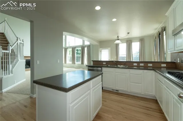 a kitchen with granite countertop a sink and white cabinets