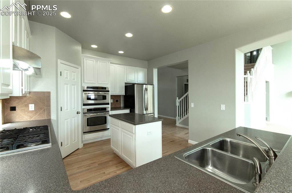 9443 St.George Road Peyton, CO 80831 - Photo 18 of 45 a kitchen with stainless steel appliances kitchen island granite countertop a refrigerator and a stove